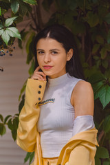 Beautiful young girl among the greens in stylish and classic yellow suit. Portrait. Fashion.