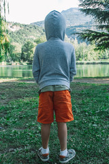 Little boy in the forest with hooded sweatshirt from behind