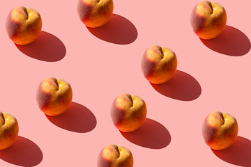 A pattern of many juicy ripe peaches on a pastel pink background. Creative layout