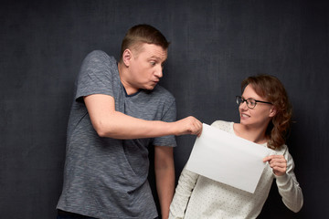 Naklejka premium Woman trying to pull paper sheet from man to herself