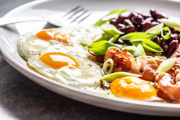 English Breakfast with eggs, bacon, beans and iyoung onion in white plate