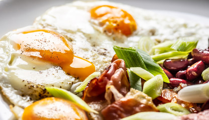 English Breakfast with eggs, bacon, beans and iyoung onion in white plate