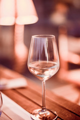 A glass of white wine on a table in a restaurant. Toned photo. Glare and light spots. Free space for text.