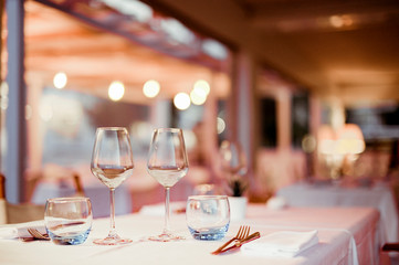 A glass of white wine on a table in a restaurant. Toned photo. Glare and light spots. Free space for text.