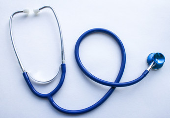 Blue stethoscope twisted rings close up on white textured paper background
