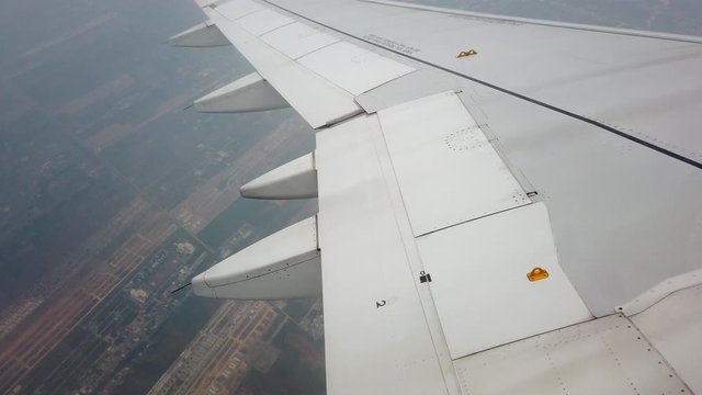 4K Aerial Point Of View From Airplane Window Of Aircraft Wing Flying Through Above City And Clouds In Overcast Sky