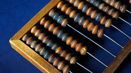 Vintage wooden abacus close up. Counting wooden knuckles. Part of the old end of the abacus on a dark blue background.