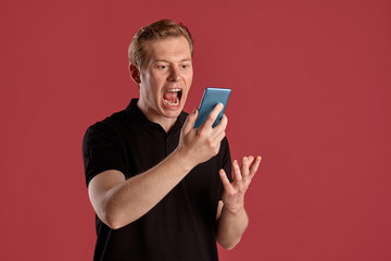 Close-up portrait of a ginger guy in black t-shirt posing on pink background. Sincere emotions.