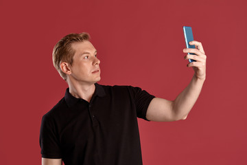 Close-up portrait of a ginger guy in black t-shirt posing on pink background. Sincere emotions.