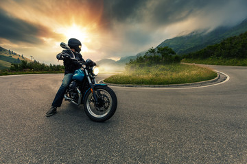 Motorcycle driver posing in Alpine landscape.