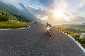 Motorcycle driver riding in Alpine landscape.