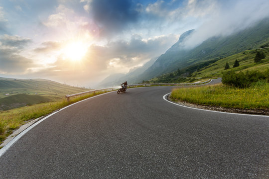 Motorcycle driver riding in Alpine landscape. Lifestyle photo with motion blur effect.