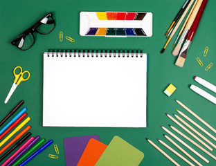 White notebook with paints and brushes for drawing. The photograph on the subject of creativity.