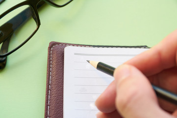 A man makes notes in a notebook with a pencil. Concept of writing thoughts on paper.