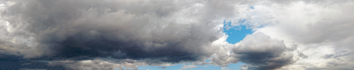 Obraz premium Summer dramatic clouds fly across a bright blue sky. Wide angle view