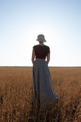 girl on a wheat field in a hat at sunset