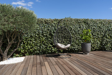 a suspended seat on a wooden floor with an olive tree