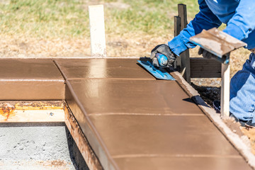 Construction Worker Using Trowel On Wet Cement Forming Coping Around New Pool