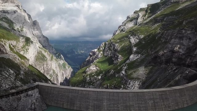 Epic grand Muttsee reservoir dam with peak Limmernsee in Linthal, aerial shot