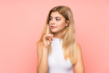 Teenager girl over isolated pink background doing silence gesture