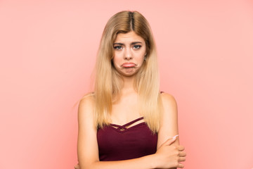 Teenager girl over isolated pink background sad