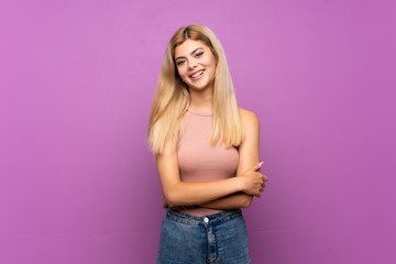Teenager girl over isolated purple background keeping the arms crossed in frontal position