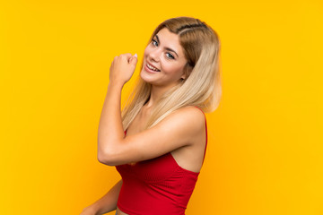 Obraz premium Teenager girl over isolated yellow background celebrating a victory