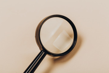 Small magnifying glass on bejge background, search symbol