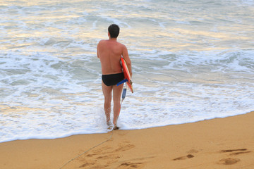 Rear view of surfer with surfboard