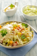 Mix fresh vegetable salad with ham and cheese and mayonnaise sauce. Large portion in a deep bowl. Ready to eat. Close up and vertical orientation.