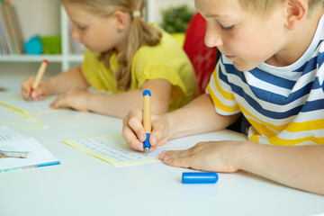 Cute schoolchildren are came back to school and learning at the table in classroom