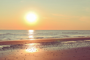 Sunset on the beach. Tinted photo in golden highlights. Sea and sandy beach. Banner, long format....