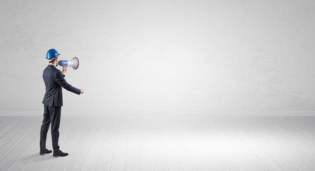 Young architect with construction helmet standing in an empty space and holding a plan