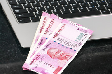 Close up view of brand new indian 2000 rupees banknotes and  laptop.