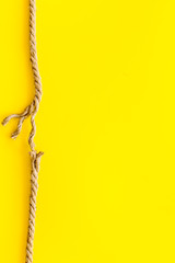 Tearing the rope under stress on yellow background top view copyspace