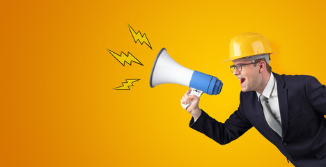 Fototapeta premium Young architect constructor yelling with megaphone and copyspace