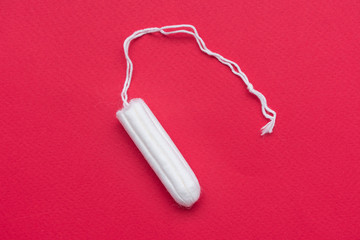 Tampon on a red background, close up, top view, copy space