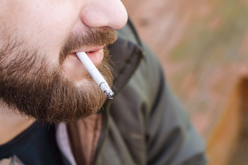 Portrait of brutal hipster adult working man after labor day with a beard close up smoking...