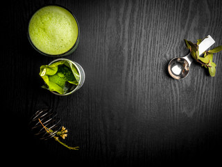 Hot green tea latte with green leaves and metal spoon, whisk, antioxidants rich drink, free space for text