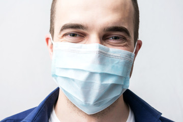 Young man in a medical mask smiles, portrait, close up
