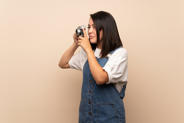 Young Mexican woman over isolated background holding a camera