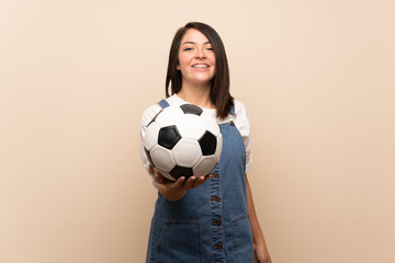 Young Mexican woman over isolated background holding a soccer ball