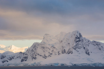 Antarctica. Paradise Harbor. Snowy mountains and clouds at sunrise.