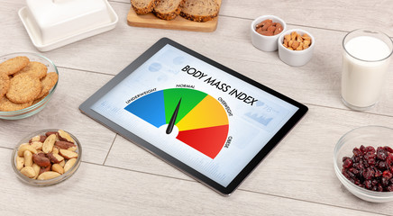 Healthy food with tablet on a wooden background with words Body Mass Index. Health concept.