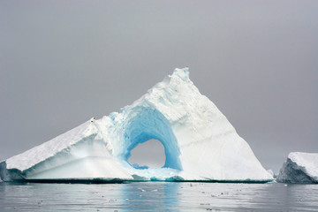Antarctica. Charlotte Bay. Giant iceberg with a hole in the middle of it.
