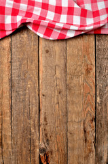 Red checkered tablecloth top frame on vintage wooden table background - view from above - vertical photo