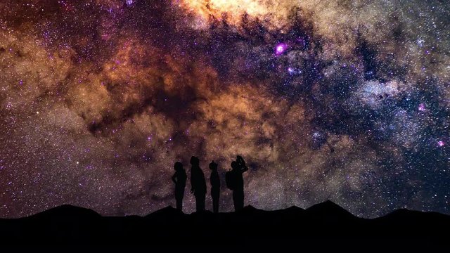 The Silhouette of people looking up to the stars and the milky way.