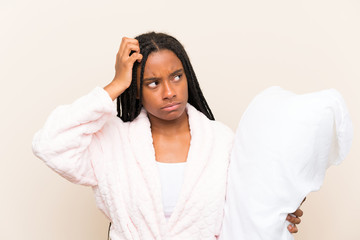 African American teenager girl with long braided hair in pajamas over isolated background having doubts and with confuse face expression
