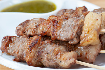 Premium roasted beef sticks serve on white plate and spicy sauce on wooden table, appetizer food before main course dish.