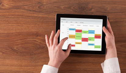 Hand holding tablet with timetable and calendar concept